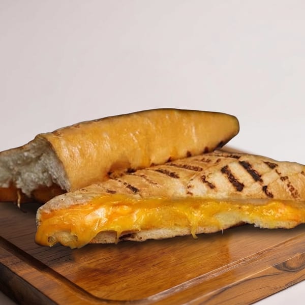 Grilled cheese sandwich on a baguette, cut in half, with melted cheese oozing out, on a wooden board.